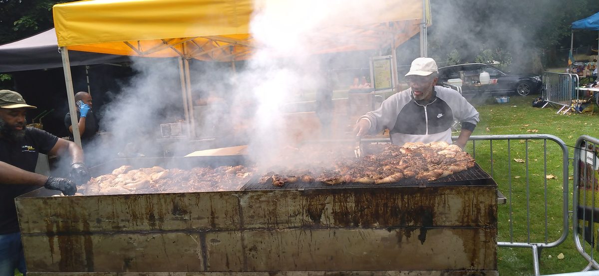 Smoking Caribbean jerk grill loaded with seasoned chicken over an open flame