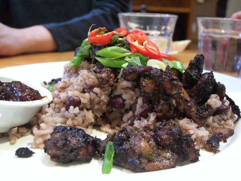 Grilled jerk chicken platter served with rice and peas and fresh chili garnish