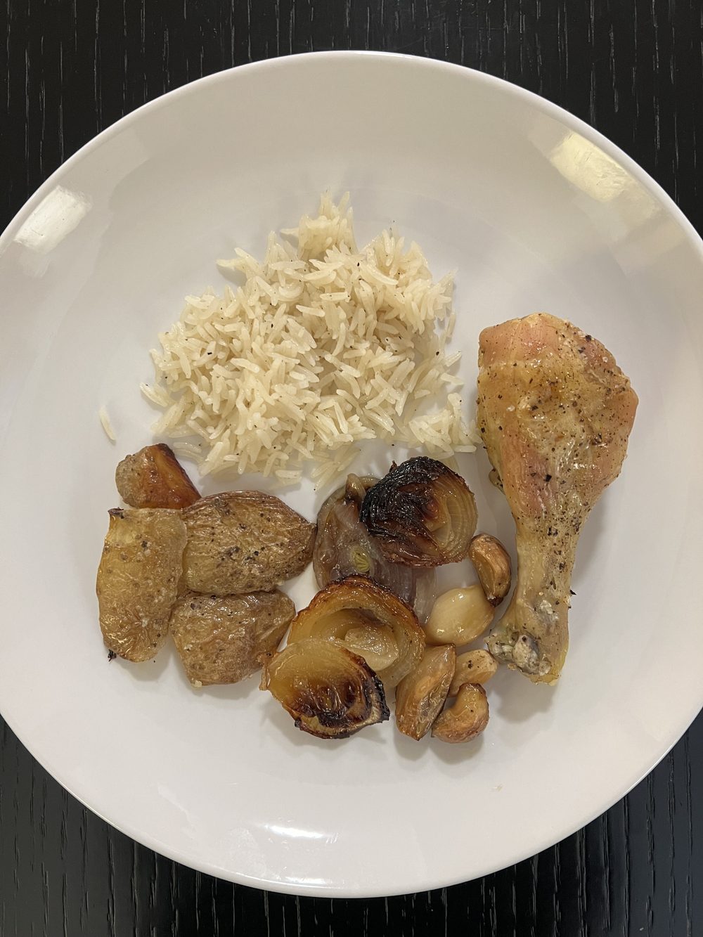 Whole roasted chicken plated with seasoned potatoes and rice